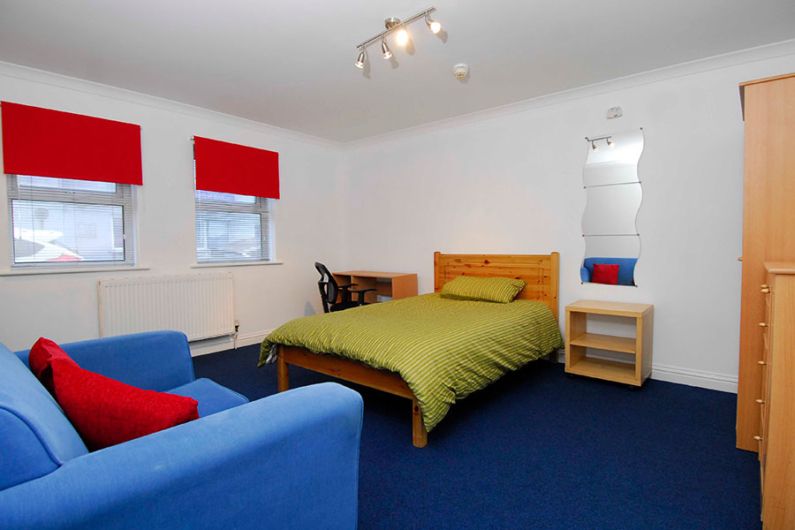 Classic studio apartment room having bed, sofa set and blue floor carpet