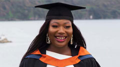 A female student wearing graduation hat and smiling