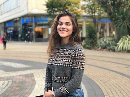 A female student smiling and standing on the road