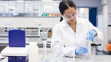 Female science lab student using glass beakers