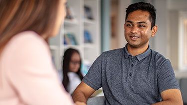 Male student talking and smiling with female student