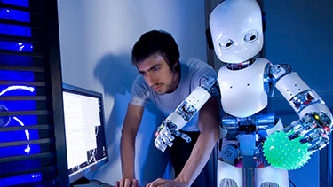 Male student programming robot in lab