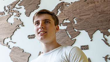 Male student standing infront of world map