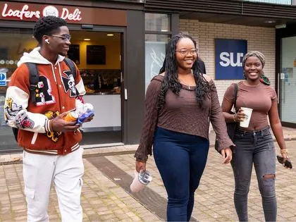 students walkin on campus outside a café “Loafers Deli” and holding water bottle and coldrink.