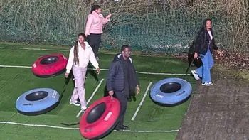 Students walk across an outdoor activity area carrying large inflatable tubes at the Snowsports Centre.